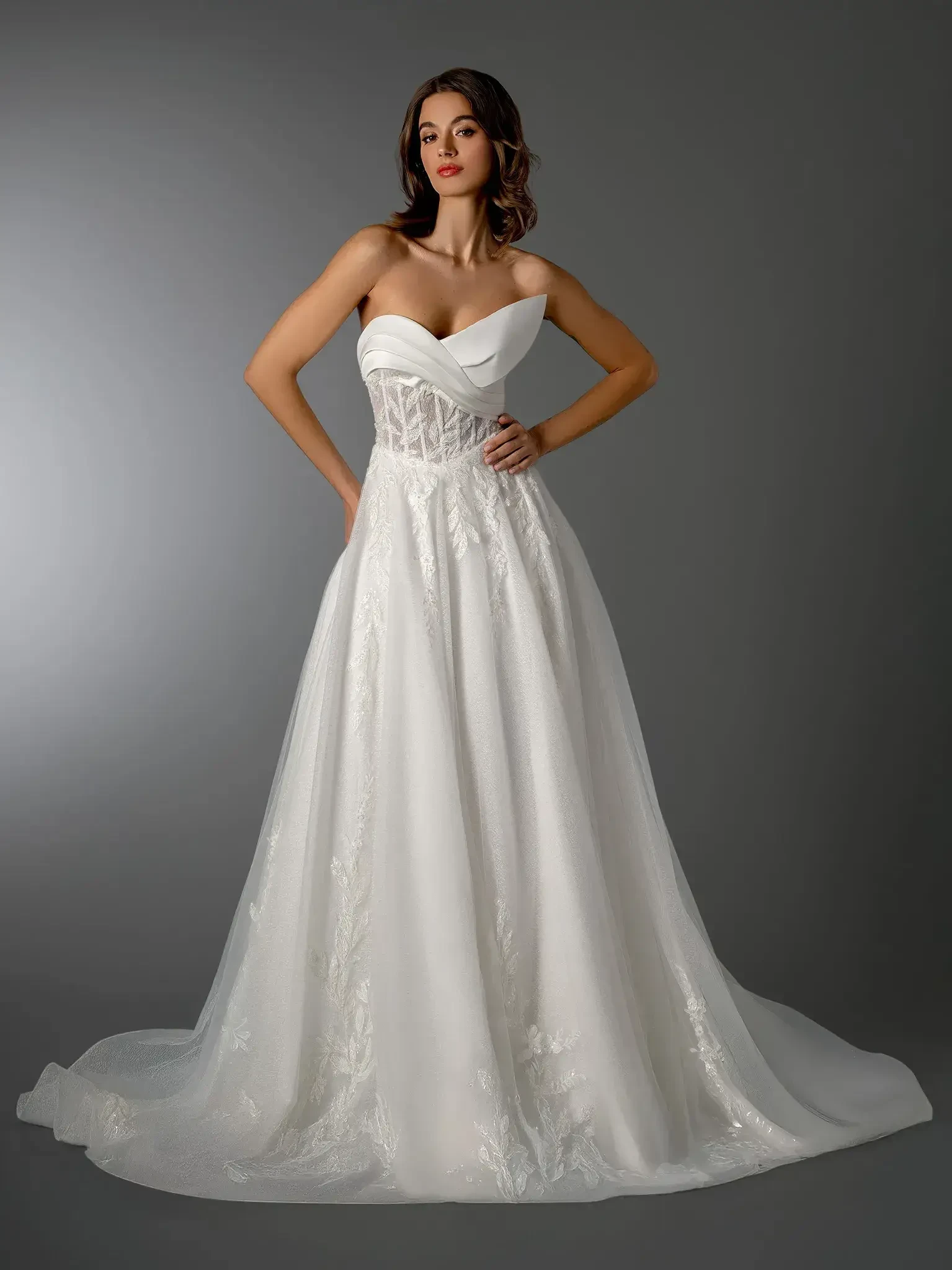 A model wearing a strapless, white wedding gown with a fitted bodice and flowing skirt.