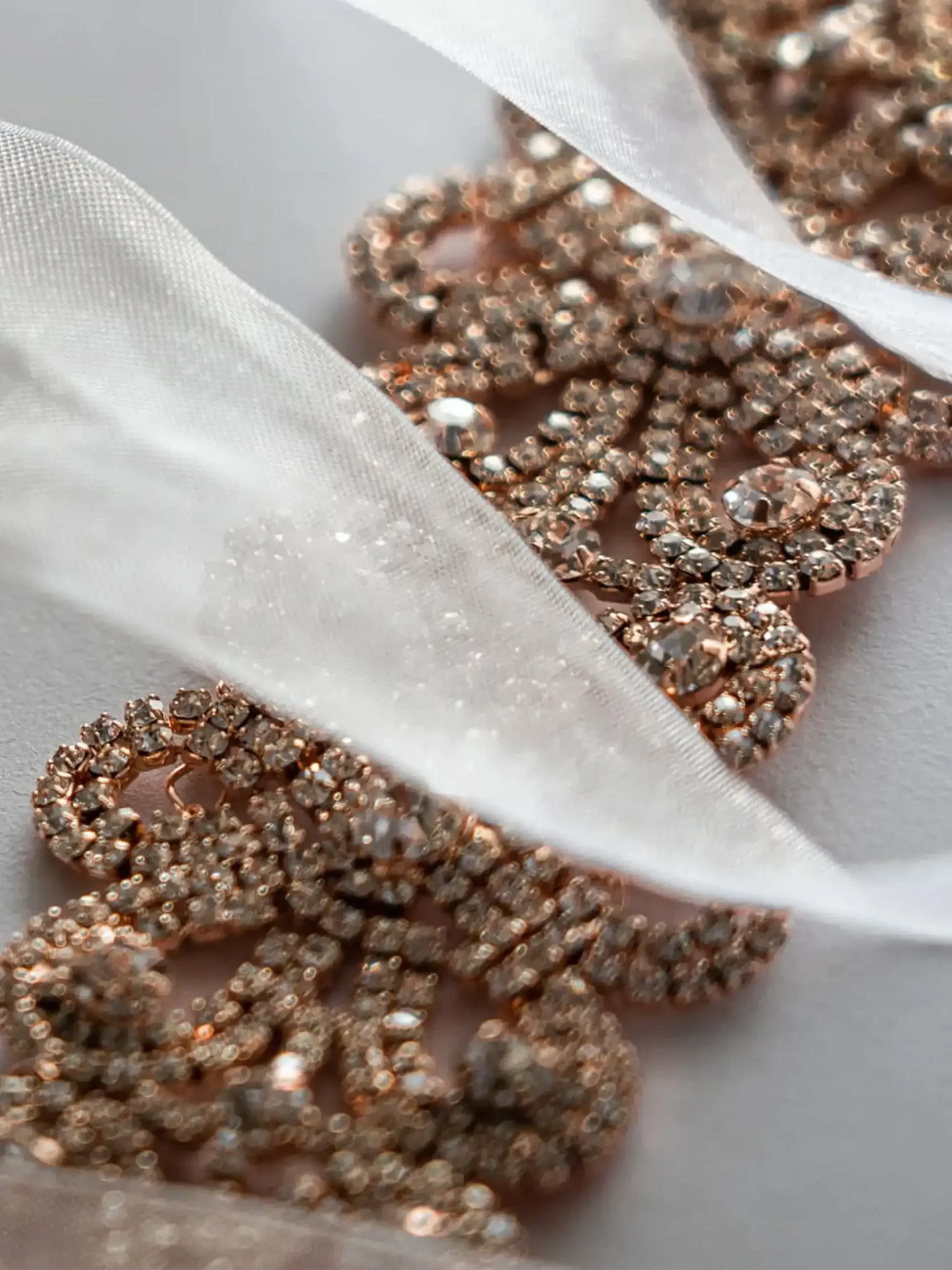 Rose gold crystal bridal belt displayed with soft white satin ribbon.